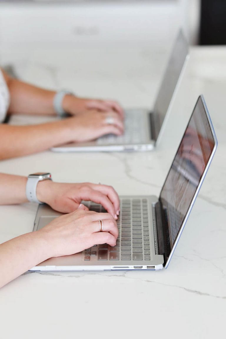 two women with hands on laptop keyboards