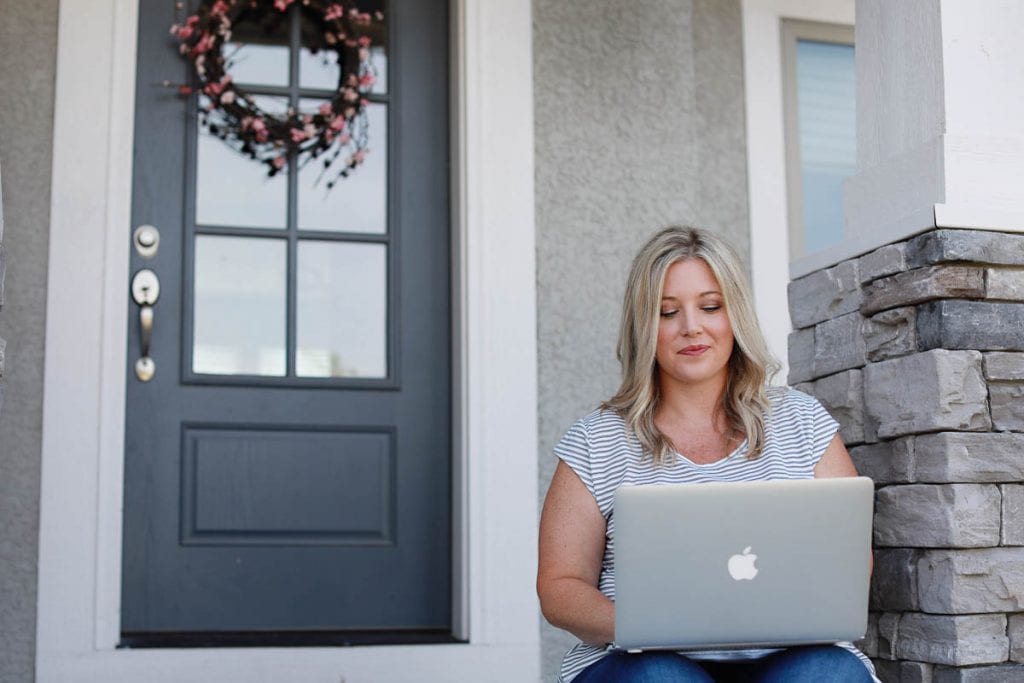 woman sitting on front steps working on a laptop