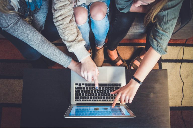 three women pointing at laptop screen
