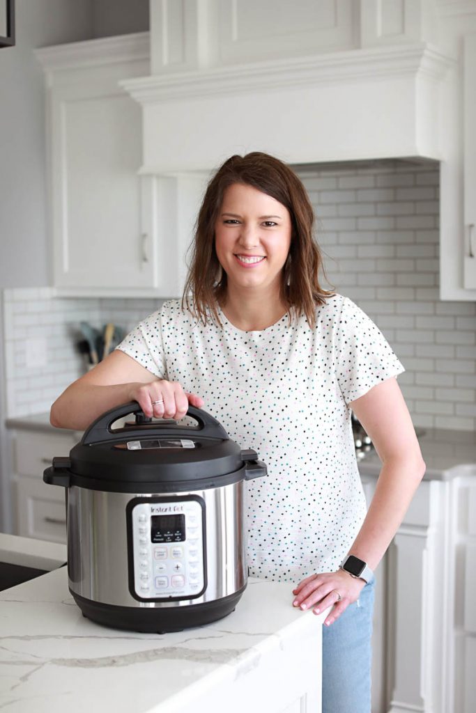 brunette woman with white sweater opening an instant pot pressure cooker