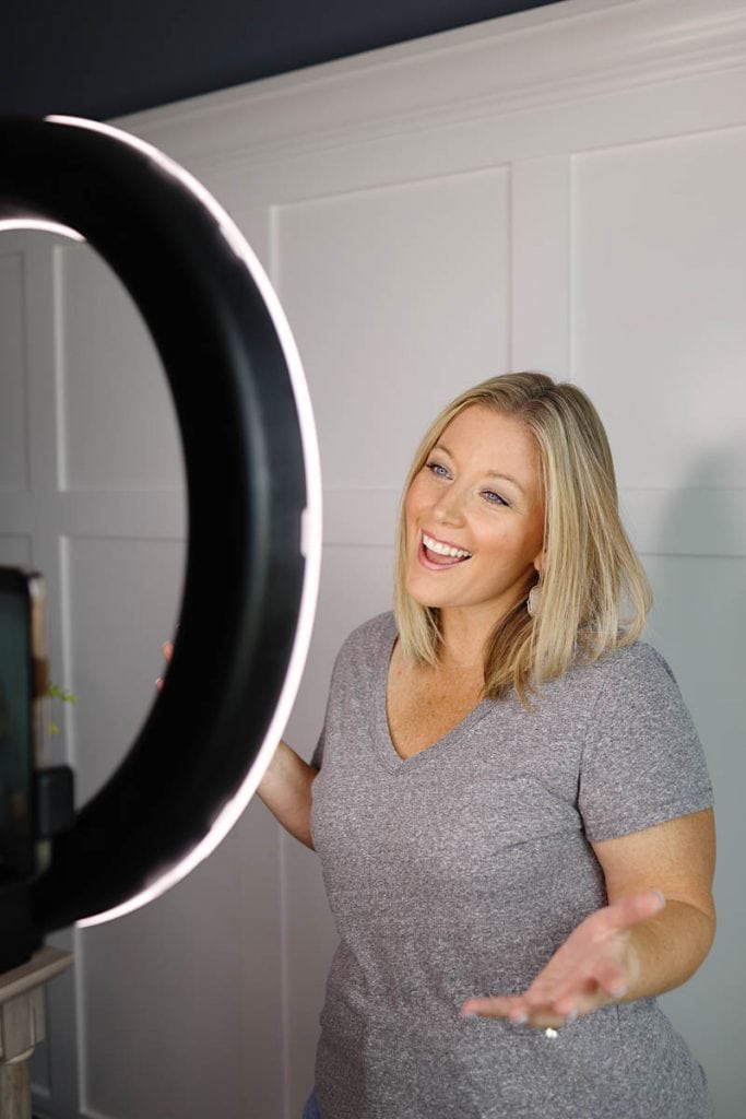 a woman smiling looking into a ring light